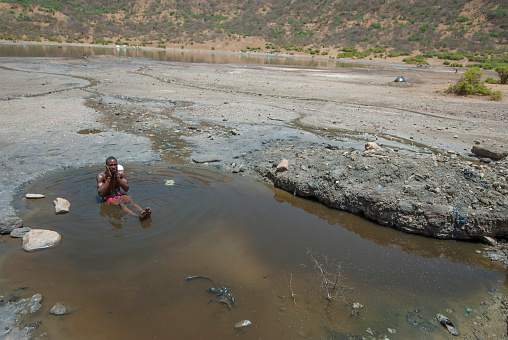 El Sod, Ethiopia - March 8th, 2012: Unidentified Borana man washes his body after mining salt from the crater lake El Sod, Ethiopia. Black salt deposit is owned by Borana tribe.