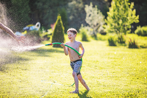 Little boy playing with water at backyard during quarantine