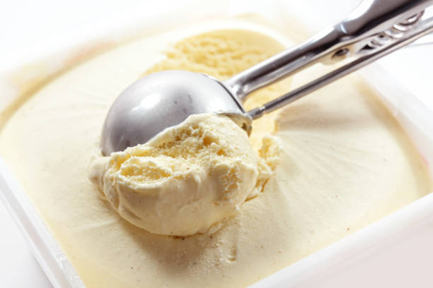 Metal scoop scrapes vanilla ice cream from the box, copy space Metal scoop scrapes vanilla ice cream from the box, copy space, selected focus, narrow depth of field scoop shape photos stock pictures, royalty-free photos & images