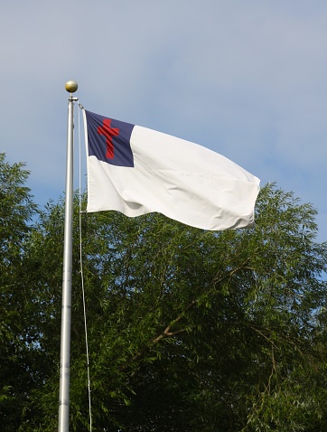 A large Christian flag on a mast at a church camp