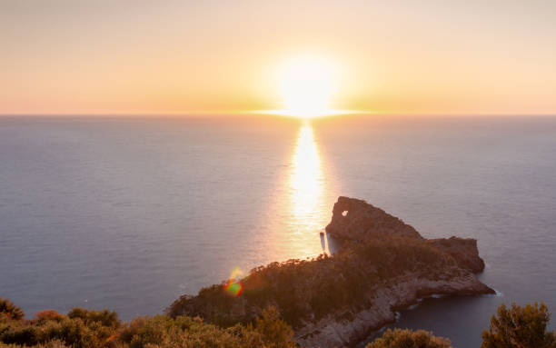 Sun setting by the horizon line of the sea in "Sa Foradada", a peninsula of the Sierra de Tramuntana in Mallorca stock photo