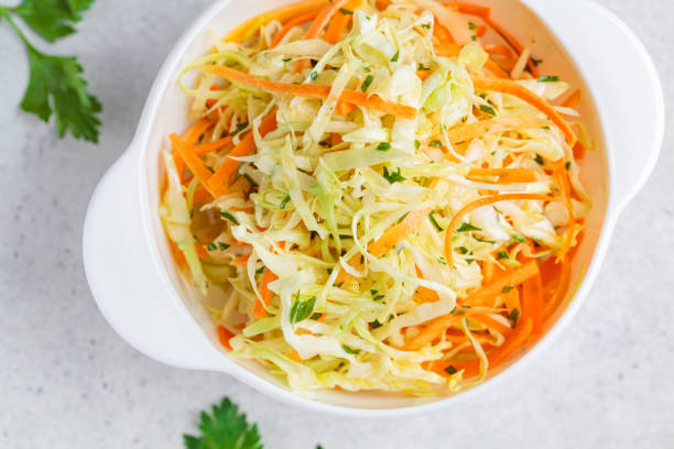 istock Fresh coleslaw salad with cabbage and carrots in white bowl, top view. 1248303377