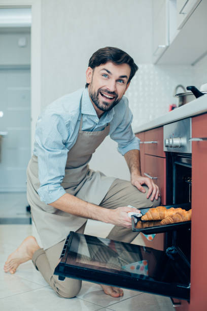 istock Barefooted man in apron cooking in the kitchen and smiling 1248303540