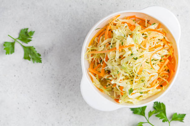 istock Fresh coleslaw salad with cabbage and carrots in white bowl, top view. 1248303541