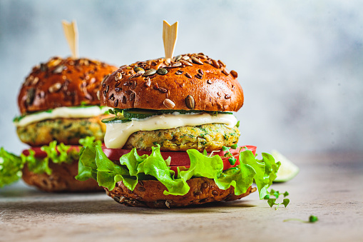 Vegan falafel burger with vegetables and sauce, dark background, copy space. Healthy  plant based food concept.