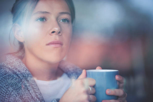 портрет женщины, сидящей и смотрящую в окно. - teenager adolescence portrait pensive стоковые фото и изображения