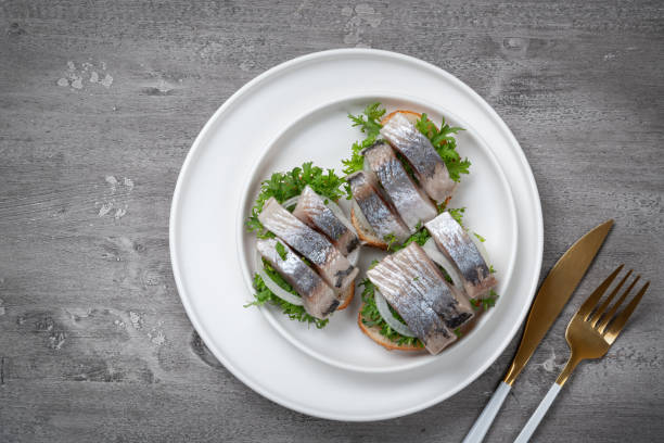 istock Delicious salted herring with onions in a white plate. Rustic style. 1248309296