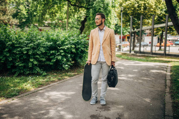 istock Young businessman with skateboard standing in park 1248310286