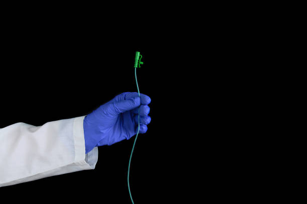 istock hand in protective surgical blue gloves holds a urological catheter on a black background. 1248310407