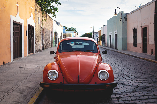 Merica, Yucatan, Mexico - 28 October 2018 - Front of red Oldtimer Volkswagen Beetle in the colonial historical streets at 'Casa Culcal Kin'