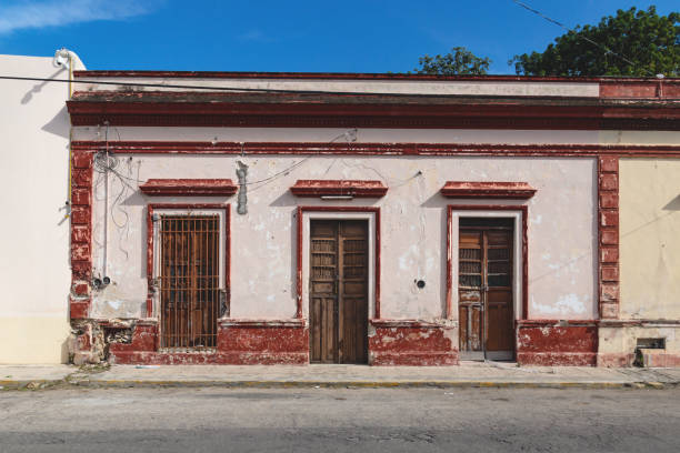 Facade of typical Mexican abandoned colonial building wth wooden doors in Merida, Yucatan, Mexico