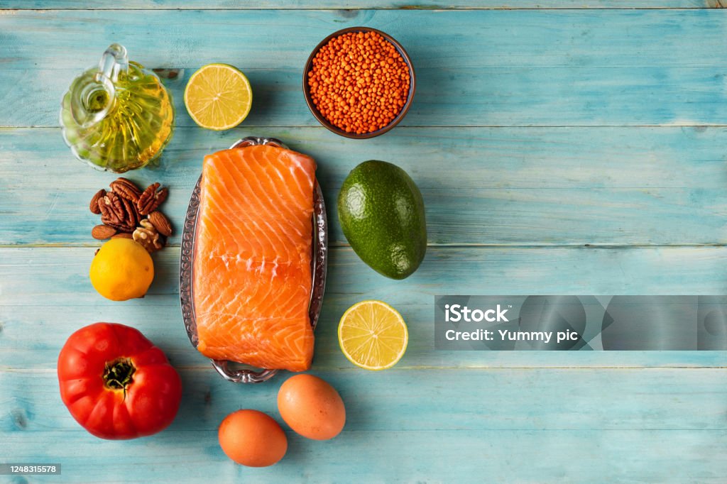 Top view of fillet of salmon around healthy diet food products. Keto diet Flat lay of fillet of salmon around healthy diet food products on light turquoise background. Keto diet concept Austria Stock Photo