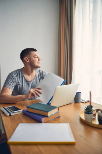 istock Handsome young man sitting and holding papers at home 1248317454