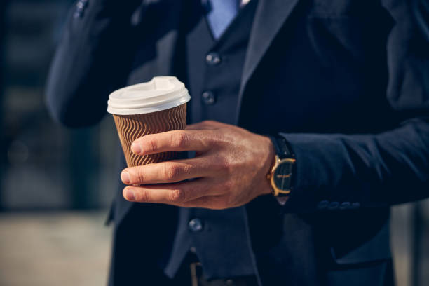 istock Male wearing blue suit and holding drink 1248319798