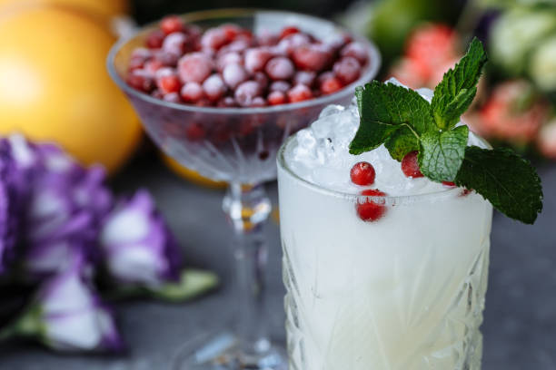 istock Summer fresh cold drinks. Ice lemonade with lemon decorated with cranberries and mint on an outdoor table. lemonade in a glass 1248334855
