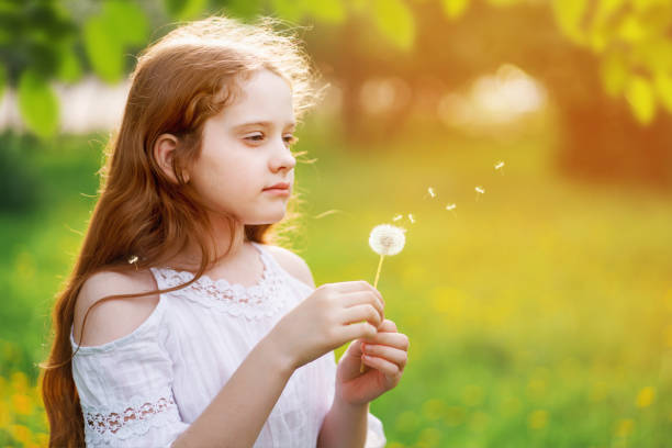 istock Little curly girl with spring flower in sunset light. 1248339004