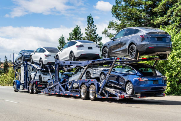 Car transporter carries new Tesla Model Y and Tesla Model 3 Jun 6, 2020 / CA / USA - Car transporter carries new Tesla Model Y (on the upper level) and Tesla Model 3 (on the lower level) vehicles on a freeway in San Francisco Bay Area tesla model 3 stock pictures, royalty-free photos & images