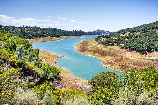 High angle view of Anderson Reservoir, a man made lake in Morgan Hill, managed by the Santa Clara Valley Water District, maintained at low level due to failure risk in case of earthquake; California