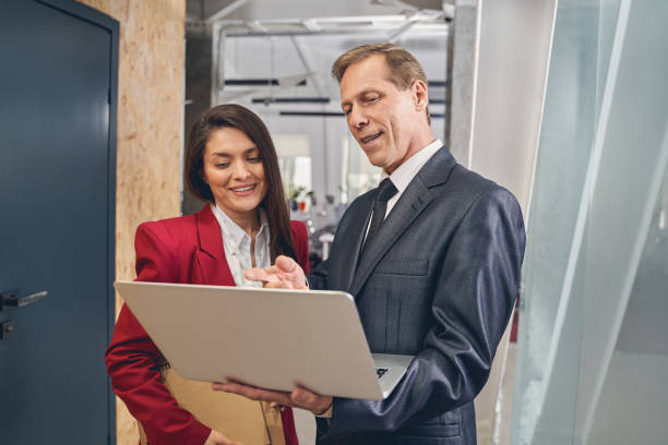 istock Cute young assistant standing near her project manager 1248378101