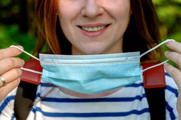 a segment of smiling woman face taking on a surgical face mask