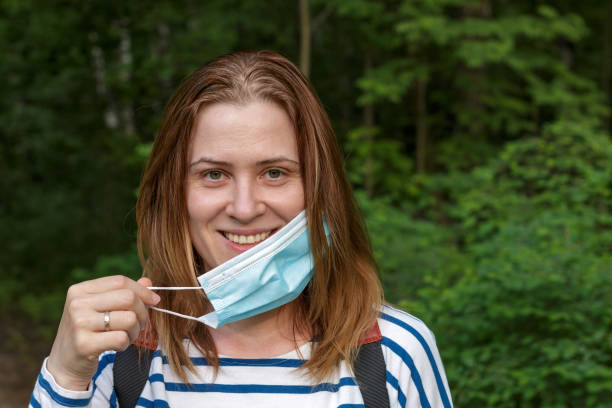 istock a smiling woman taking off a surgical face mask 1248382892