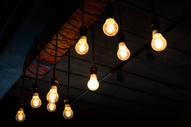 istock Beautiful vintage luxury light bulb hanging decor glowing in dark. 1248385973