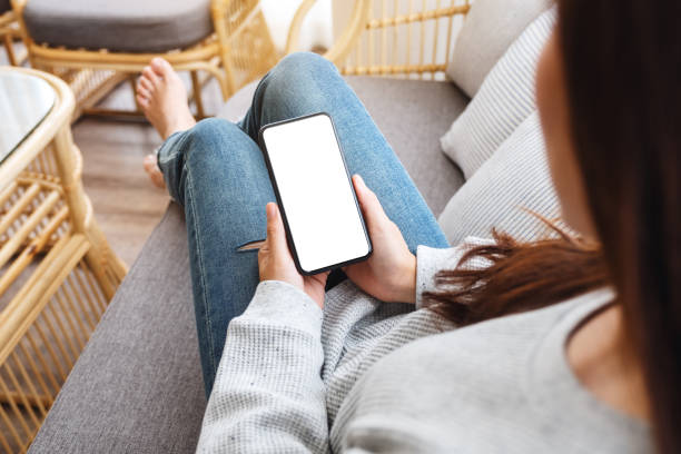 istock a woman holding mobile phone with blank desktop white screen while lying on a sofa at home 1248391781