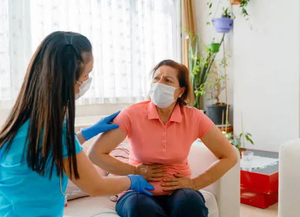 Photo of Abdominal pain patient woman having medical exam with doctor on illness from stomach cancer, irritable bowel syndrome, pelvic discomfort, Indigestion, Diarrhea, GERD (gastro-esophageal reflux disease)