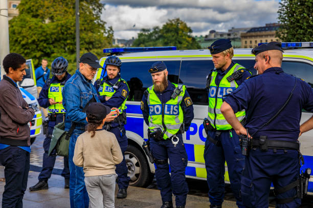 group of uniformed swedish male police officers talking to a little dark haired child in the center of stockholm sweden - child little boys male caucasian imagens e fotografias de stock