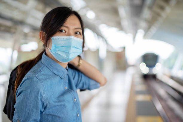 istock Young asian woman with face mask standing on platform and wait for light rail transit 1248398399