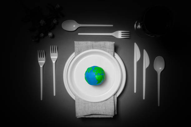 istock Serving table with colored Earth planet and black and white plastic plates, spoons, forks and wine glass with petroleum oil. Ecology Concept for Earth Hour, Earth Day, Ocean Day and other ECO dates. 1248405096