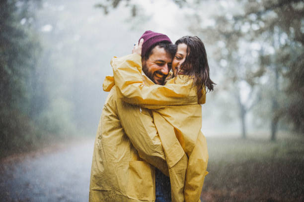 istock Young loving couple in raincoats embracing on rain. 1248409924