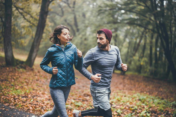 istock Young athletic couple running during cold day in forest. 1248409991