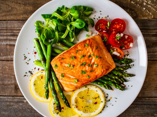 istock Fried salmon steak and asparagus on wooden table 1248417346