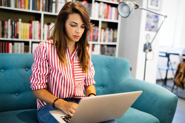istock Happy woman using laptop while sitting on a sofa 1248420515