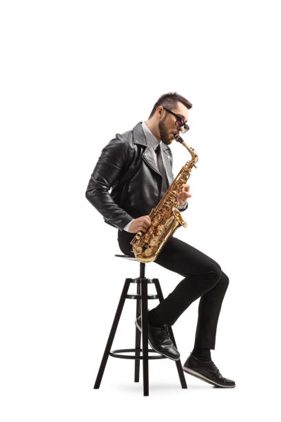 istock Man in a leather jacket sitting on a chair and playing a saxophone 1248433336