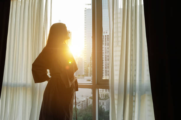 istock young girl in bathrobe opens window transparent curtains in apartment 1248433385