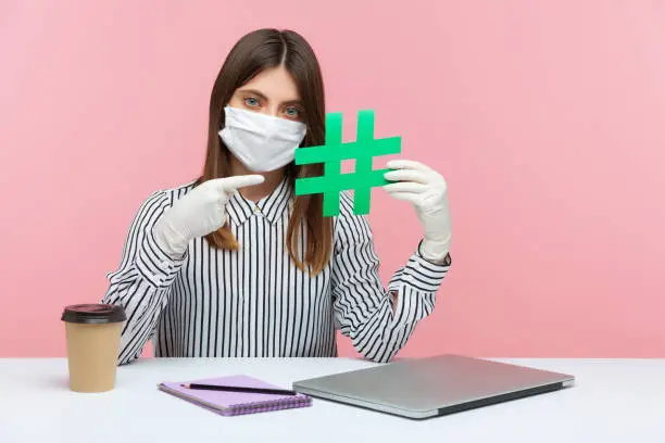 Photo of Viral topic about covid-19, self-isolation. Woman employee sitting safe healthy with hygienic face mask