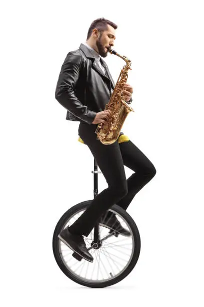 Man riding a unicycle and playing a saxophone isolated on white background