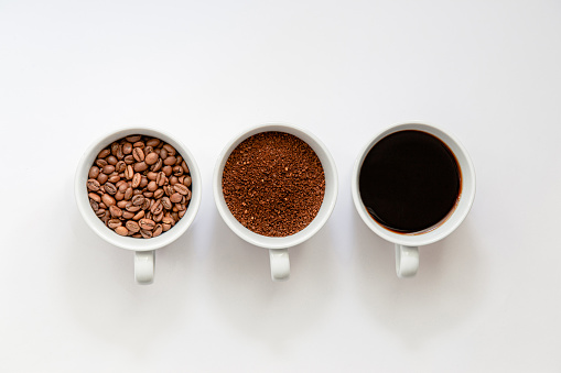 Flat lay view of, coffee beans, grinded coffe and ready to drink coffee in a cup