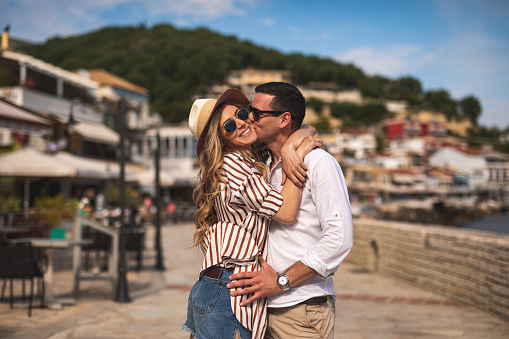 Young man kissing girlfriend in old town by the sea