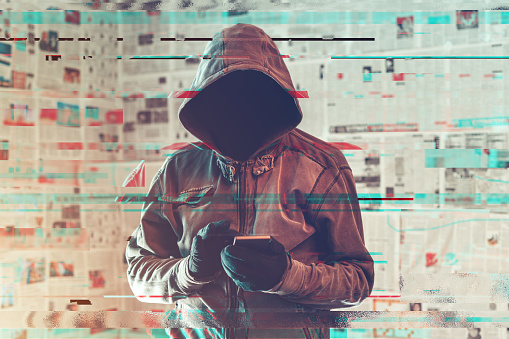 Persona hacker con capucha usando el teléfono inteligente en el concepto infodemic photo