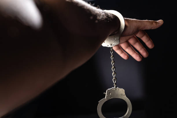 криминальная рука с наручниками на черном фоне - bail bond стоковые фото и изображения