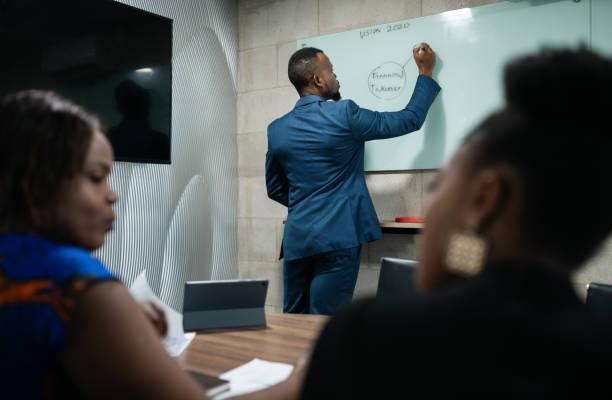 африканский менеджер делает презентацию доски во время презентации офиса - writing whiteboard men businessman стоковые фото и изображения