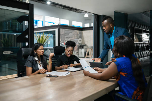 reunião de empresário africano com sua equipe em torno de uma mesa de diretoria - indian culture manager men asian ethnicity - fotografias e filmes do acervo