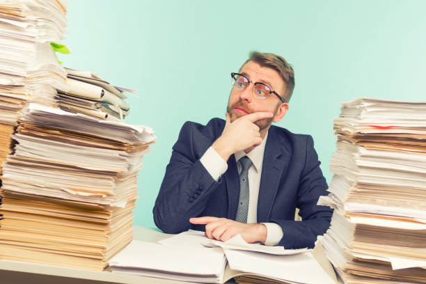 istock Shocked businessman sitting at the table with many papers in office 1248447768