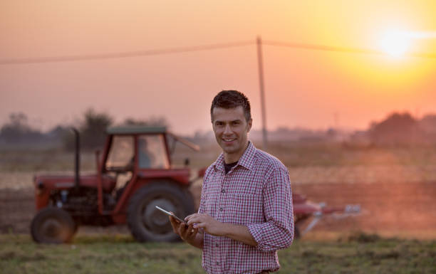 istock Farmer with tablet in front of tractor in field 1248448245