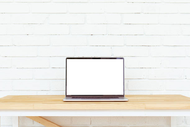istock Laptop with white blank screen on wooden table. Open space. 1248451000