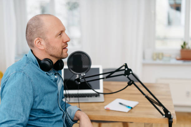istock Man seated at a desk alongside podcast equipment 1248454071