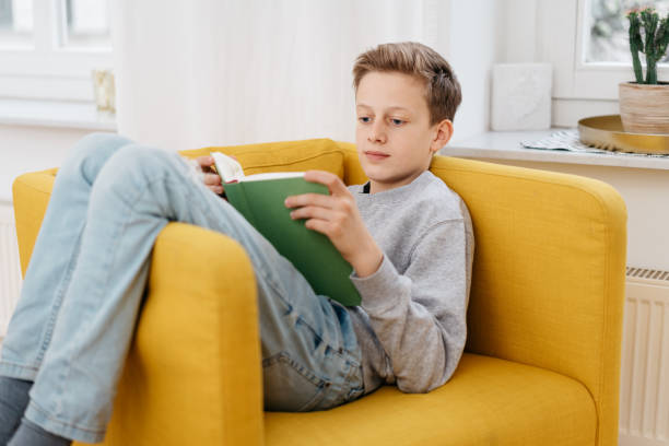 istock Young boy relaxing at home reading a book 1248454318